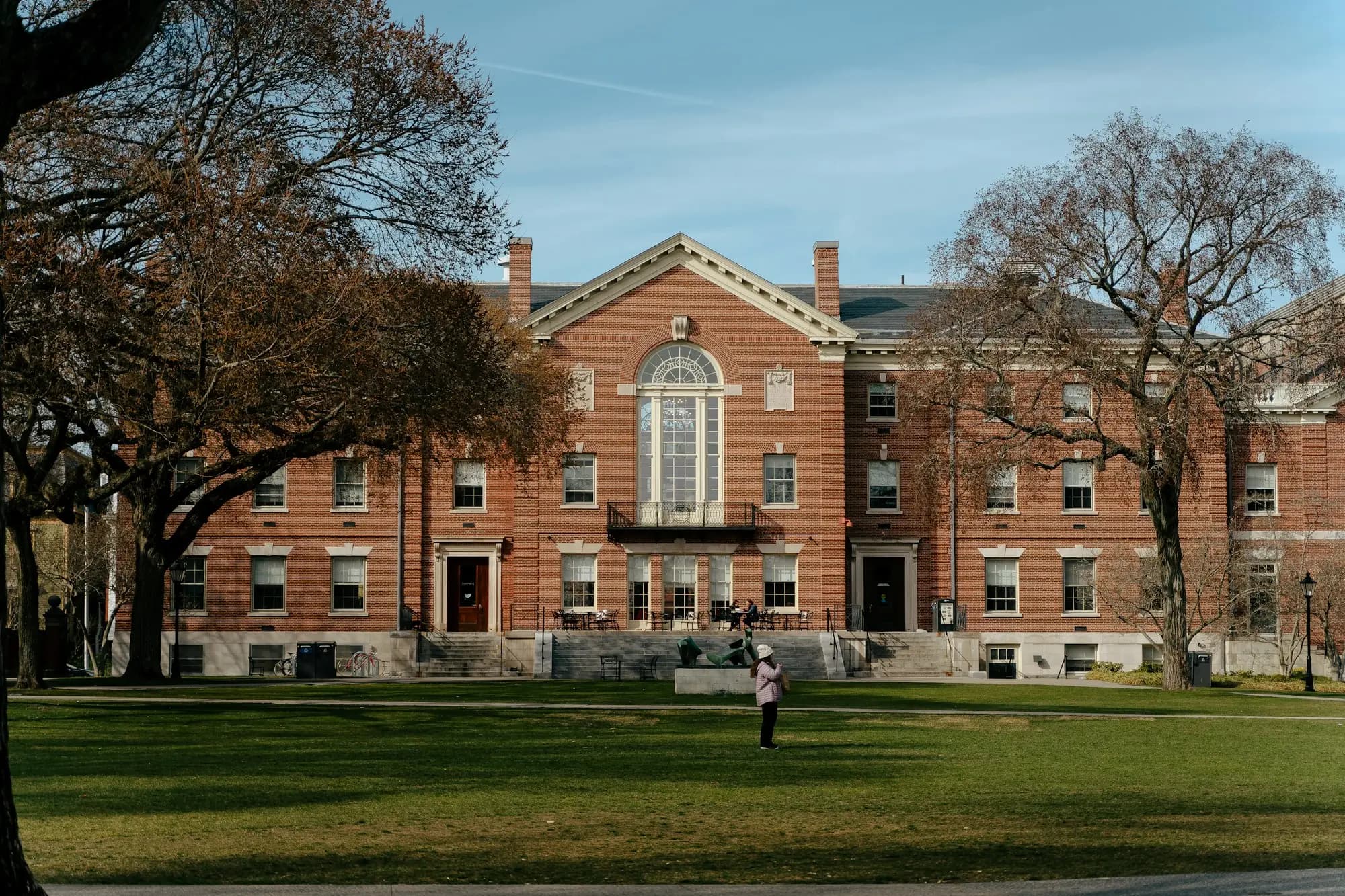 A red-brick university hall across a campus lawn