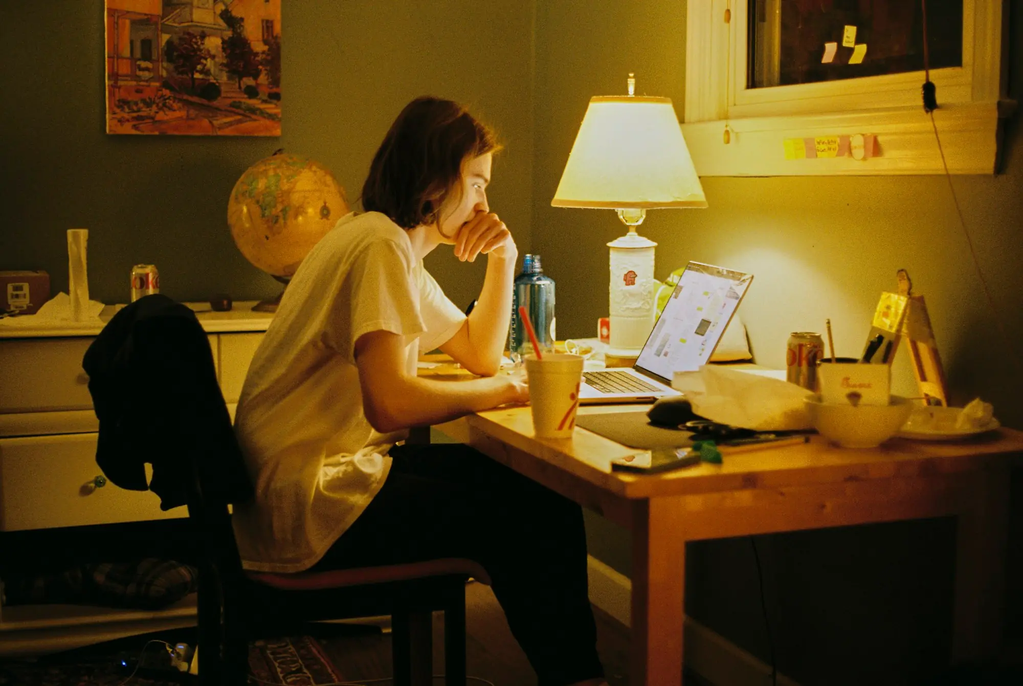 A student studying at a desk by lamplight